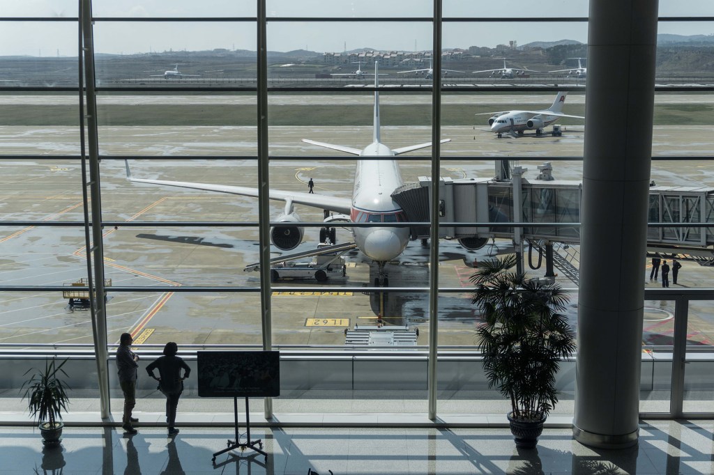 Passengers stand in front of an Air Koryo plane at Pyongyang Airport on April 17, 2017