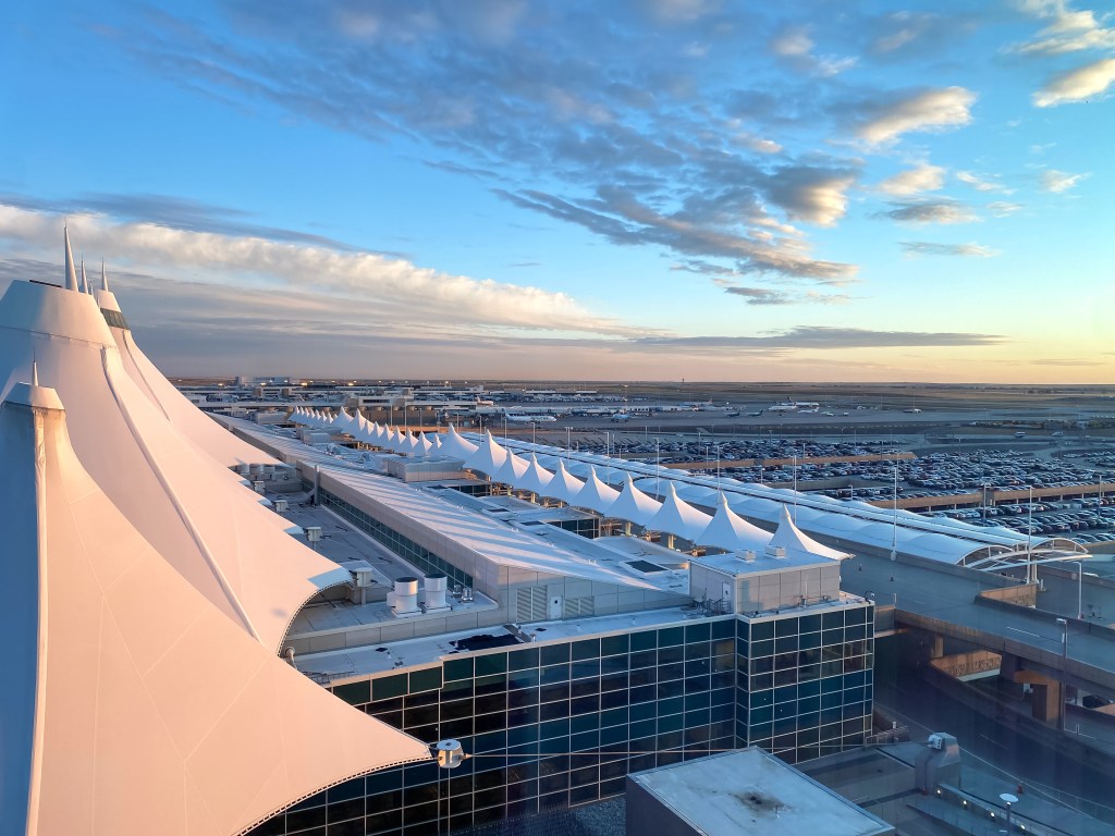 Denver International Airport viewed from the window of the Westin Hotel, with the white-canopied terminal, parking lot, and airplanes on the runway